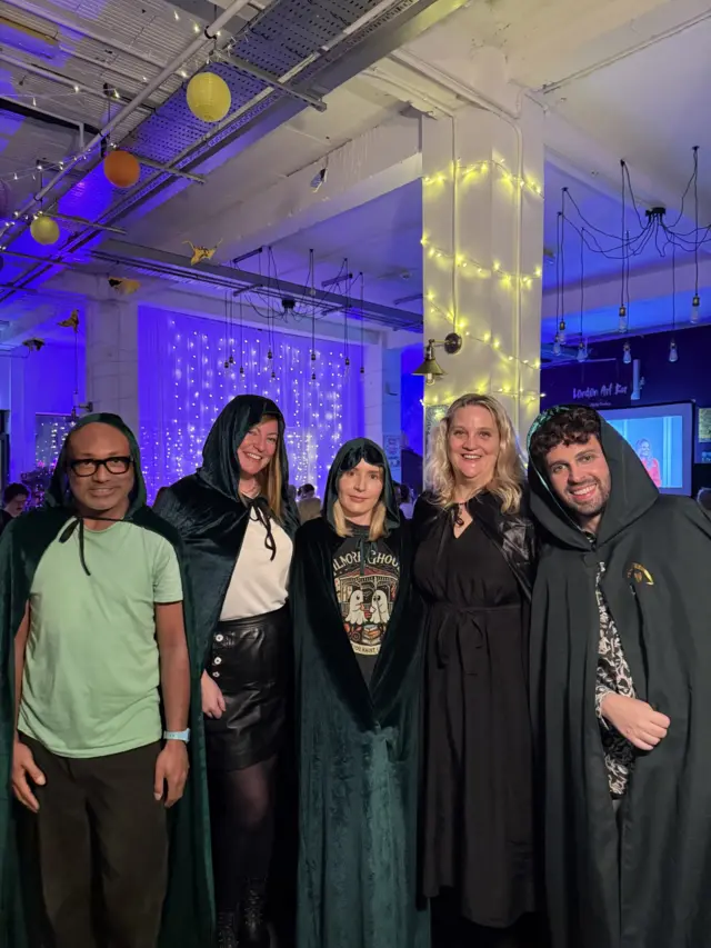 Five people in a pub wearing traitors' cloaks