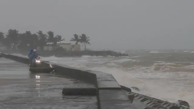 People watch waves crashing on the beach ahead of Typhoon Kalmaegi in Cua Dai, Da Nang, central Vietnam