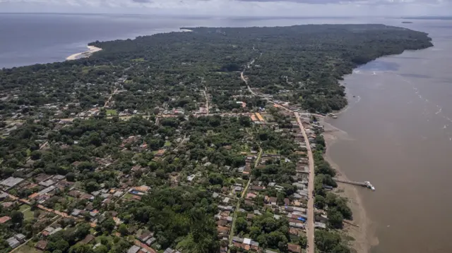 Aerial view of suburb of Belém, houses and roads nestled in Amazon rainforest. Spit of land extends out into the sea into the distance.