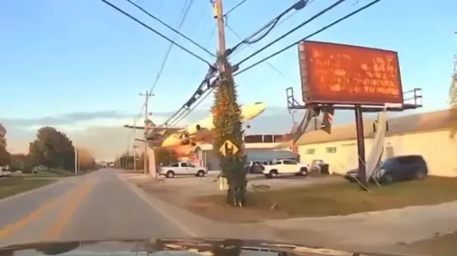 A plane in the process of crashing, it is about to hit some fuel tanks in the distance. The image is a screengrab of dashcam footage.