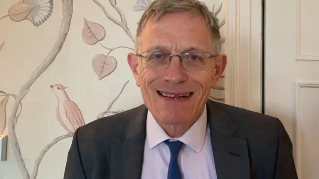 Simon Calder wearing a suit and looking at the camera