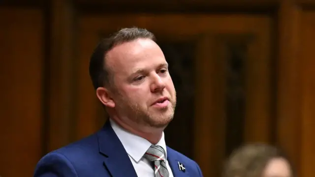 Ben Maguire standing in the commons. It is a shot of him from shoulders up