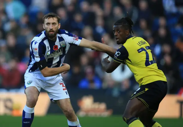 Nathaniel Phillips of West Bromwich Albion (L) jostles with Greg Leigh of Oxford United