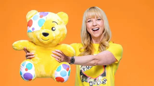 Sara Cox holding out a Pudsey Bear