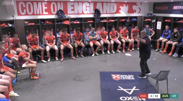 Shaun Wane speaks to his England team in the dressing room as the players sit down