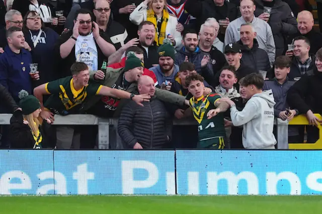 Reece Walsh of Australia jumps over the advertising board and into the stand