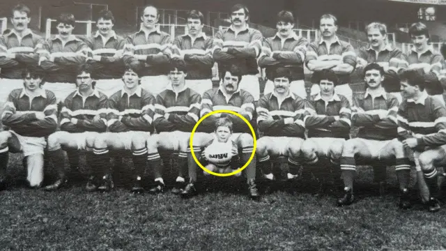 Black and white image of rugby team with a yellow circle around Steve Tandy as a child