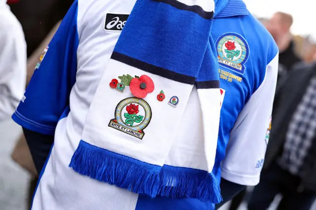 A fan of Blackburn Rovers wears a poppy on his scarf