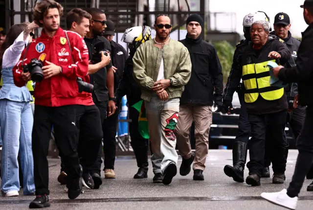 Lewis Hamilton walks into the paddok surrounded by people in the Sao Paulo paddock