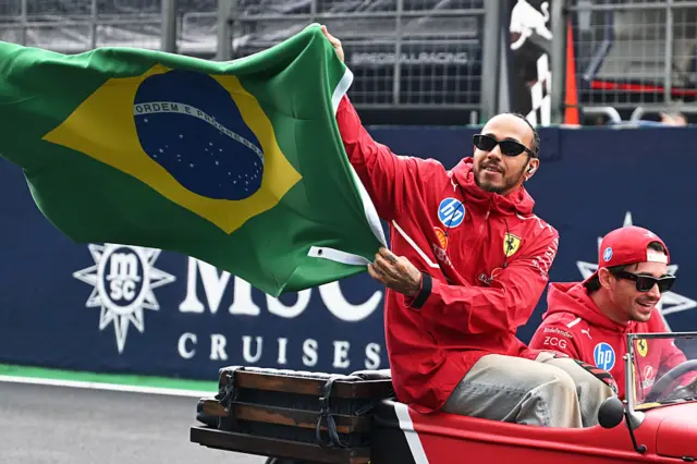 Lewis Hamilton holds up a Brazilian flag
