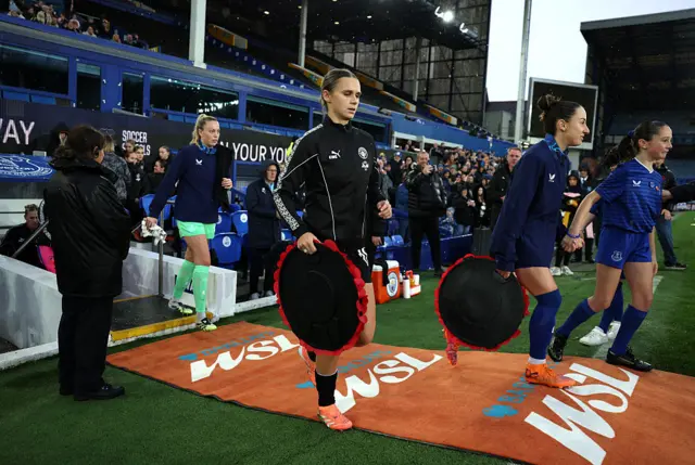 Kerstin Casparij of Manchester City walks out onto the pitch whilst holding a poppy wreath ahead of Remembrance Day