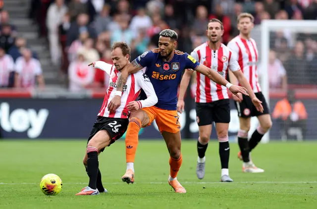 Mikkel Damsgaard of Brentford is challenged by Joelinton of Newcastle United during the Premier League match between Brentford and Newcastle United at Gtech Community Stadium on November 09, 2025 in Brentford, England.