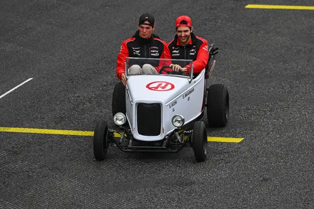Oliver Bearman and Esteban Ocon drive a little car during the drivers' parade
