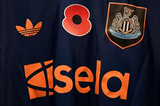 Newcastle United shirt with a poppy on.