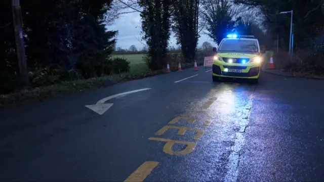 A police car parked at the entrance to a cordon.