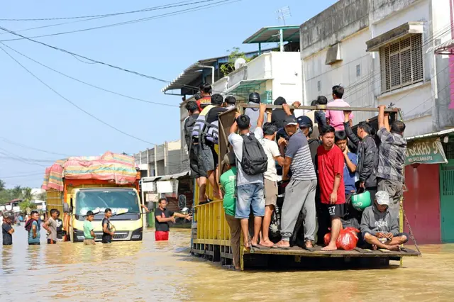 People use trucks to wade through a road in a flooded area on 30 November 2025 in Sumatra.
