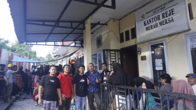 People posing for a photo outside a yellow building