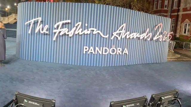 un signe qui dit "prix de la mode 2025"assis sur le tapis bleu.