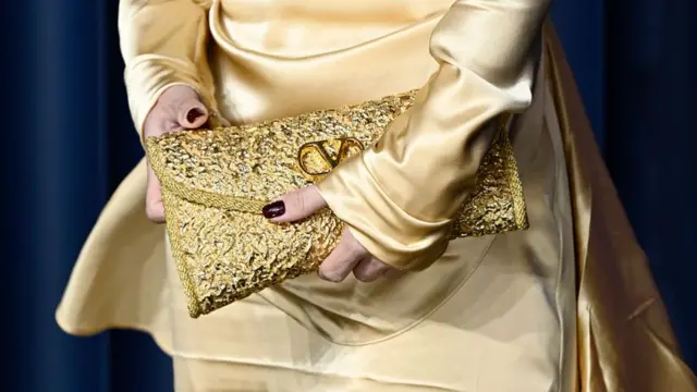 Lilly Allen holding a sparkling gold clutch bag