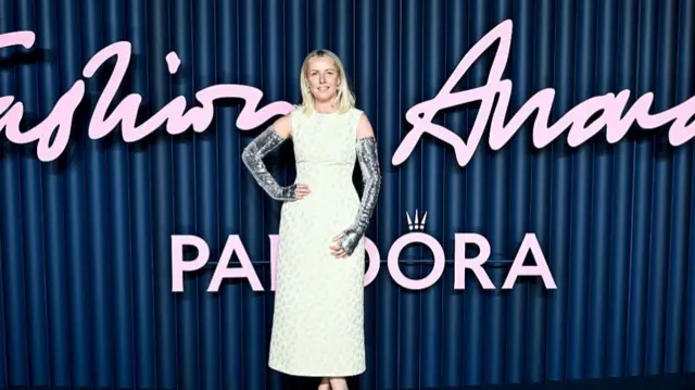 British Fashion Council CEO Laura Weir wears a yellow dress and sparkly sleeve gloves