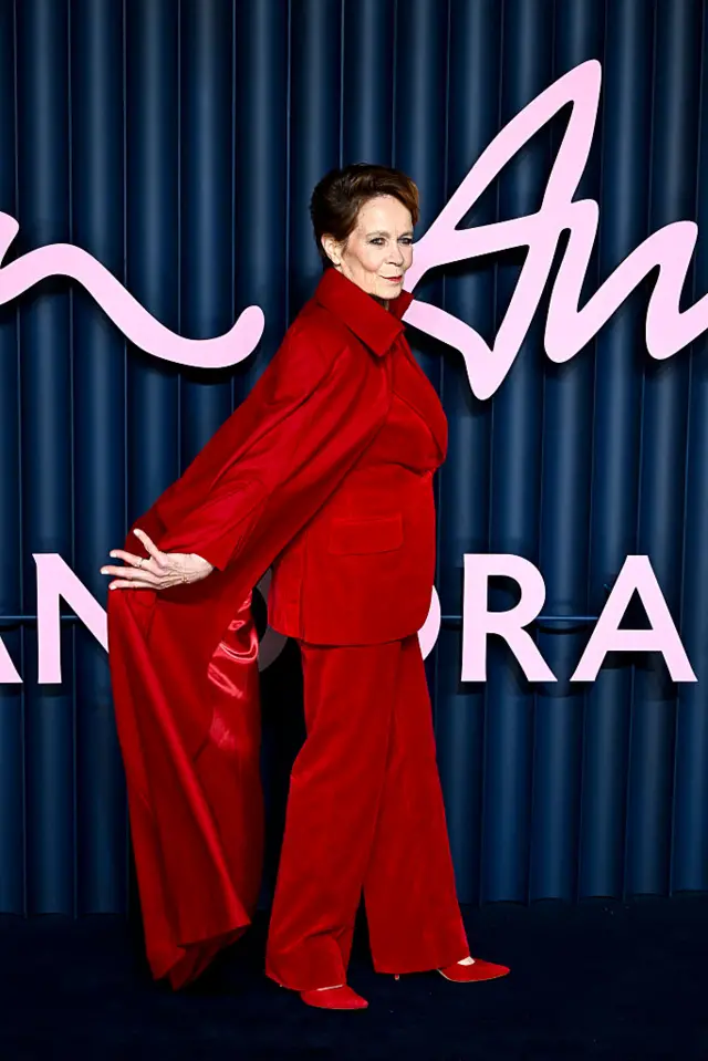 Celia Imrie throws back her red cape as she poses