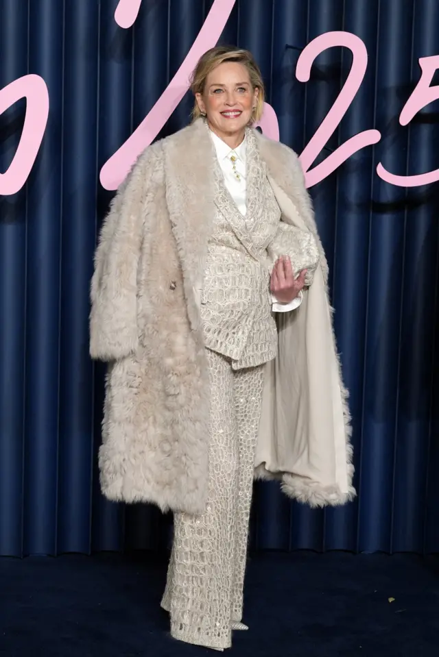 Sharon Stone wears a furry, white coat and a textured, white animal-print a trouser suit