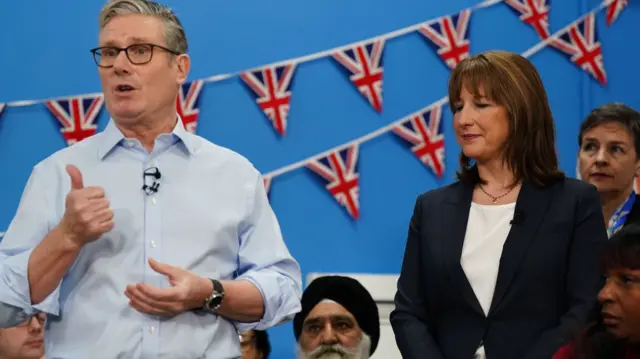 Chancellor of the Exchequer Rachel Reeves stands next to Prime Minister Sir Keir Starmer as he speaks during a visit to the Benn Partnership Centre, a community centre in Rugby,