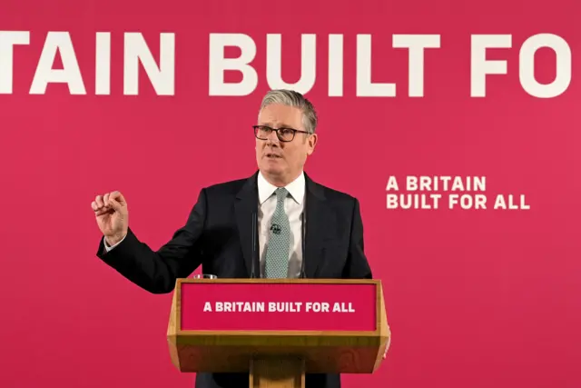 The prime minister standing in front of a red background that reads: A Britain built for all