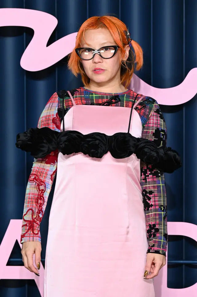 Yuka Hirac wears a pink dress with tartan-inspired sleeves and black frills