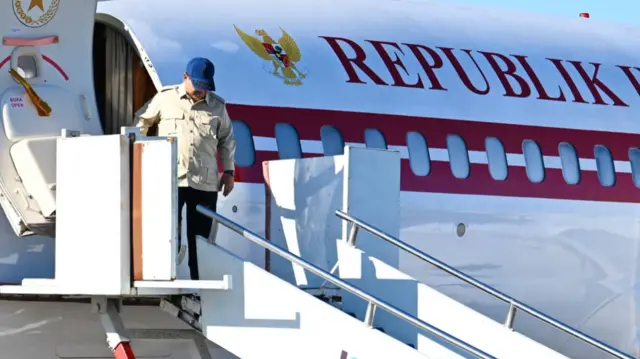 Prabowo wearing a blue cap stepping out from his plane