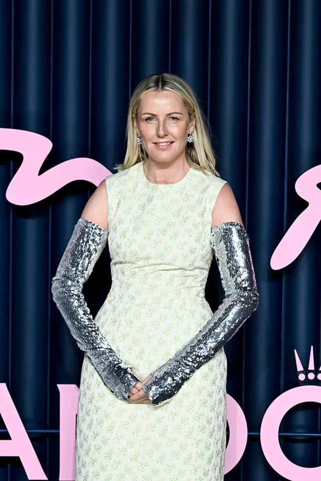 British Fashion Council CEO Laura Weir wears a yellow dress and sparkly sleeve gloves