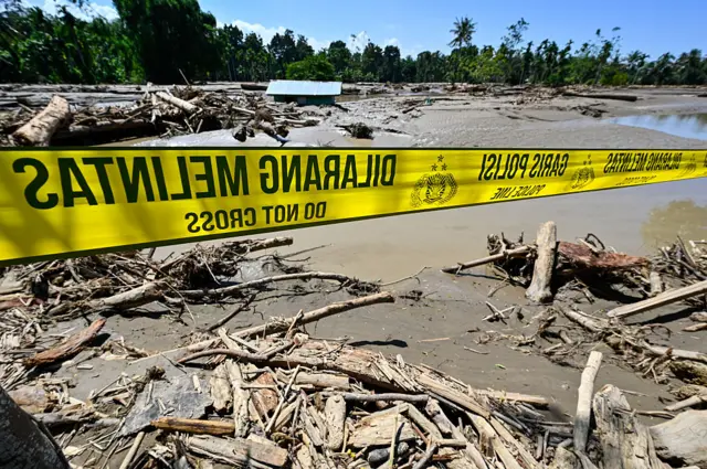 Police tape is seen above mud and debris in a flood affected area in Meureudu, Pidie Jaya district in Indonesia's Aceh province on 30 November 2025.