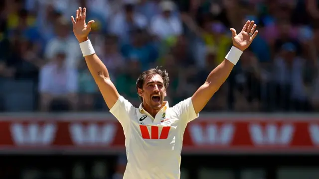 Mitchell Starc raises his arms in celebration