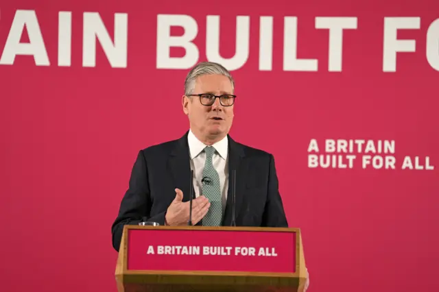 The prime minister standing in front of a red background that reads: A Britain built for all
