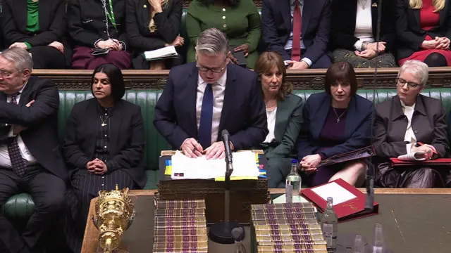 Keir Starmer stands during Prime Minsiter's Questions. Members of his front bench can be seen sat behind him
