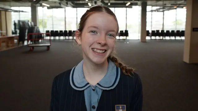 A schoolgirl smiles at the camera