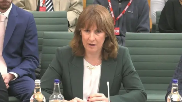 Rachel Reeves sits at a desk and speaks into a microphone