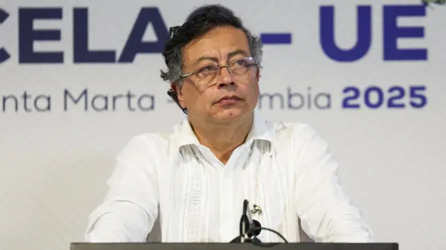 Gustavo Petro in a white shirt stands at a podium