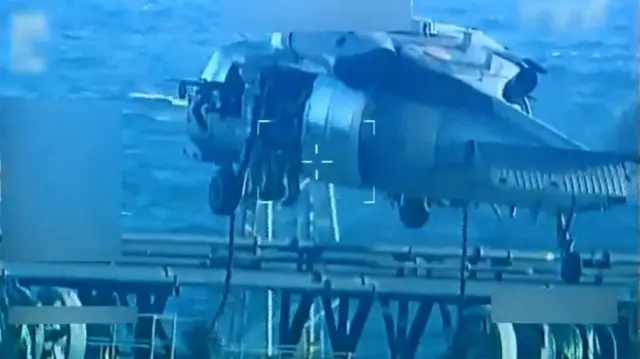A helicopter flies over a ship sailing on the ocean