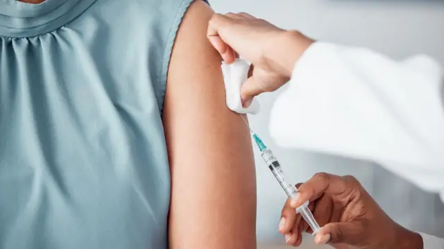 The torso of a person getting a flu jab in their arm