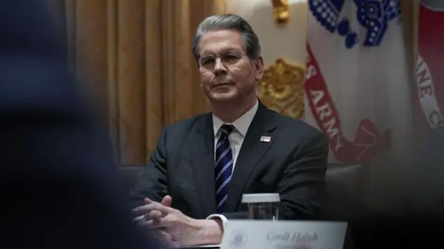 Bessent sat at table with hands clasped