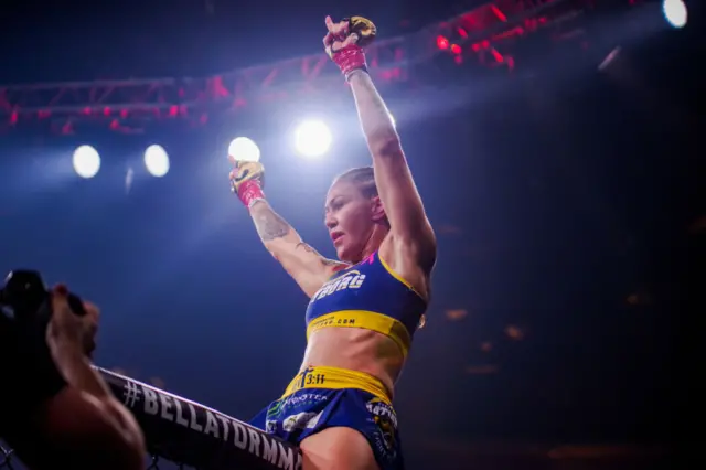 Cris Cyborg sitting on the edge of the cage