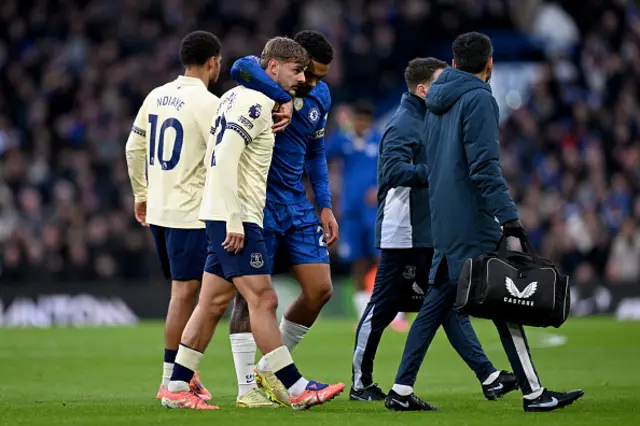 Kiernan Dewsbury-Hall of Everton is helped off the pitch by Reece James