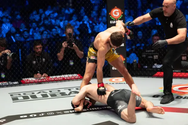Baris Adiguzel stand over Dean Garnett as he goes for his leg