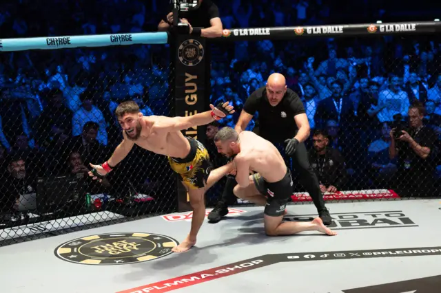 Baris Adiguzel is celebrating while Dean Garnett still hangs onto his leg