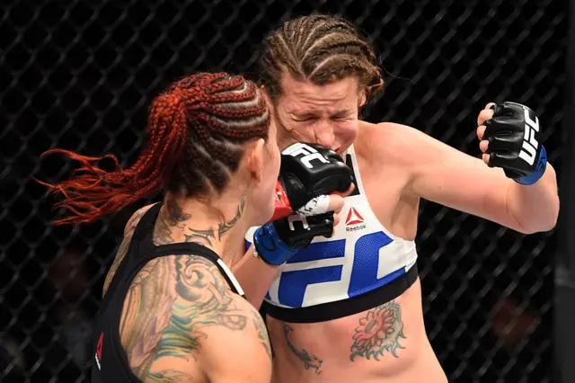 Cris Cyborg lands a punch on her opponent face which contorts from the pressure