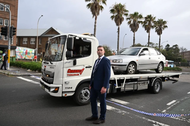 A car under police escort is removed from the scene where two gunmen opened fire at Bondi Beach