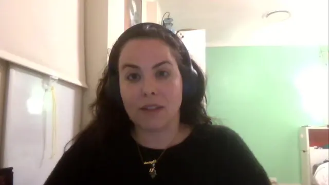 Amie Liebowitz wears a black jumper and headphones as she appears on a Zoom call