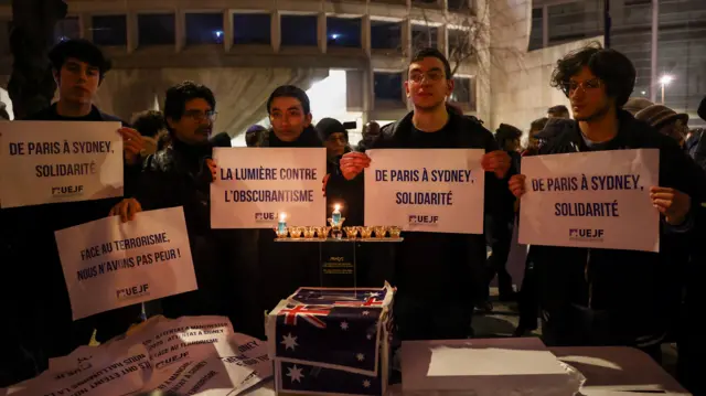 People holding signs saying they sand in solidarity with those affected by the shooting in Australia