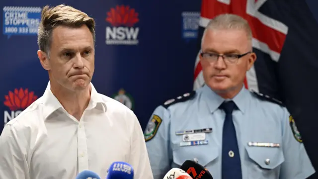 Two men standing next to each other in front of a number of microphones